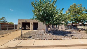A building with a brick exterior, a large tree in front, and a clear blue sky. - Mtn-View Home w/ Large Yard & BBQ in Sierra Vista! (Sierra Vista)