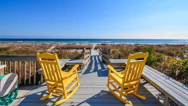 A wooden deck with two rocking chairs facing a beach. - Stay at Bunker Hill, a spacious 4-bedroom oceanfront house in charming Topsail Beach! (Topsail Beach)