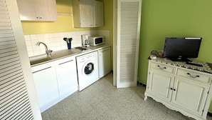 A compact kitchen with a washing machine, microwave, and a television on a table. - Apartment near the beach with balcony for 4 people (Argelès-sur-Mer)