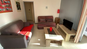 A living room with two sofas, a coffee table, a TV, and a door leading to another room. - Beachfront apartment for 4 with loggia in Argelès-sur-Mer (Argelès-sur-Mer)