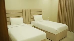 Camera d'albergo con due letti, ognuno dotato di testiera e biancheria da letto bianca.