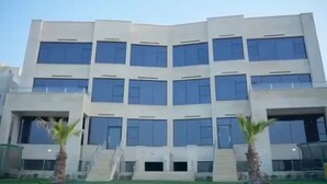 Un edificio moderno de varios pisos con fachada simétrica, ventanas amplias y una escalera central.