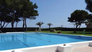 A rectangular swimming pool with a clear blue water surface, surrounded by a paved deck with white borders. - Beachfront Apartment with Garden, Pets Allowed (Miami Playa)