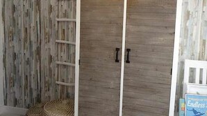 A room with a wooden wardrobe, a ladder, and a wicker basket. - Beachfront Apartment with Garden, Pets Allowed (Miami Playa)
