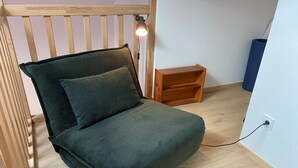 Et hyggeligt, lille værelse med en seng, et natbord og en lampe.