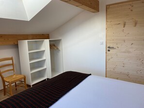 A bedroom with a bed, a wooden chair, a wardrobe, and a wooden door. - New 78m² duplex, 2 bedrooms, pellet stove, WIFI, parking, sleeps 5 - Arâches-la-Frasse (Arâches-la-Frasse)