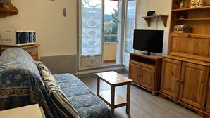 Een woonkamer met een bank, een televisie, een kast en een klein tafeltje.