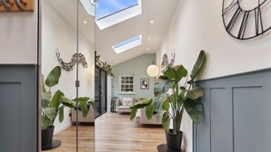 Un interior moderno con piso de madera, una puerta de vidrio que conduce a una sala de estar y una planta grande en el centro.