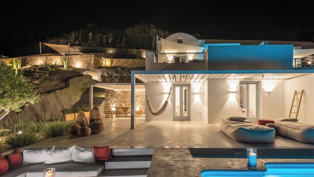 Ett modernt hus med en swimmingpool, utomhusmöbler och en trappa som leder upp till en balkong.