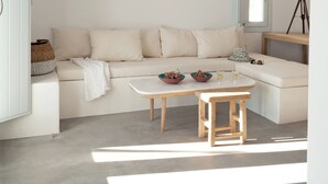 Ett minimalistiskt vardagsrum med en soffa, ett litet bord och ett teleskop.
