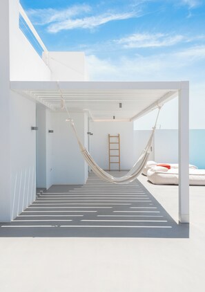 A white outdoor area with a hammock, a ladder, and a bed with pillows. - Exclusive dual-suite unit with private infinity pools at Santorini Heights (Pirgos Kallistis)