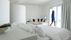 Ett modernt hotellrum med en säng, en soffa och ett stort fönster med gardiner.