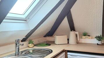 A kitchen with a skylight, a sink, a toaster, and a small refrigerator.
