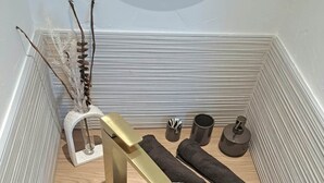 A bathroom with a stone sink, gold fixtures, and a mirror. - To complete (Colmar)