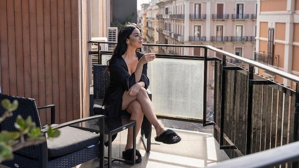 A balcony with a chair and a table, overlooking a cityscape with buildings. - B&Z Luxury (Bari)