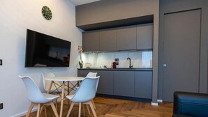 A compact living space with a dining area, kitchenette, and a flat-screen TV mounted on the wall. - B&Z Luxury (Bari)