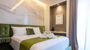 A hotel room with a large bed, green headboard, white bedding, a green throw blanket, and a heart-shaped towel arrangement. - B&Z Luxury (Bari)