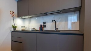 A modern kitchen with grey cabinets, a black faucet, and a small potted orchid on the counter. - B&Z Luxury (Bari)