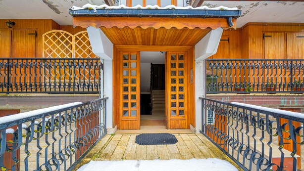 Ein hölzernes Gebäude mit Balkon und einer zur Inneneinrichtung führenden Tür.