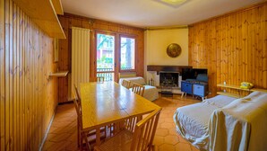 Ein holzmöbel-ausgestattetes Zimmer mit Esstisch, Stühlen, einem Bett, einem Fernseher und einem Kamin.
