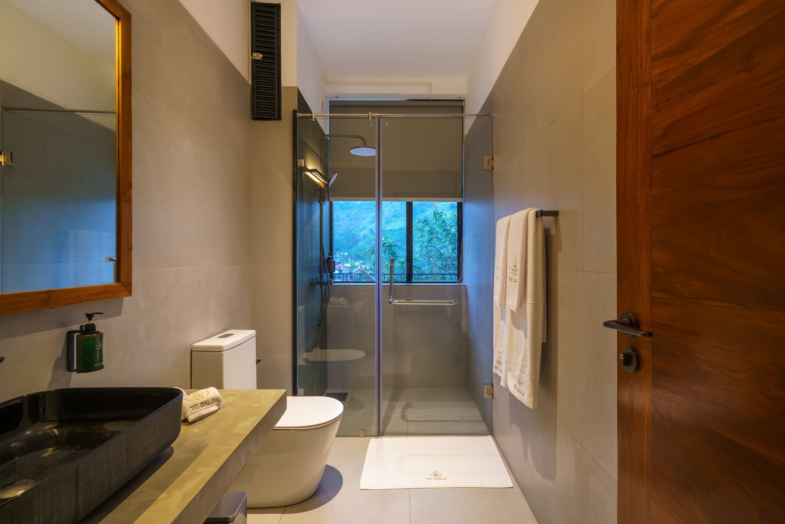 A modern bathroom with a glass-enclosed shower, a large mirror, a sink, and a toilet.