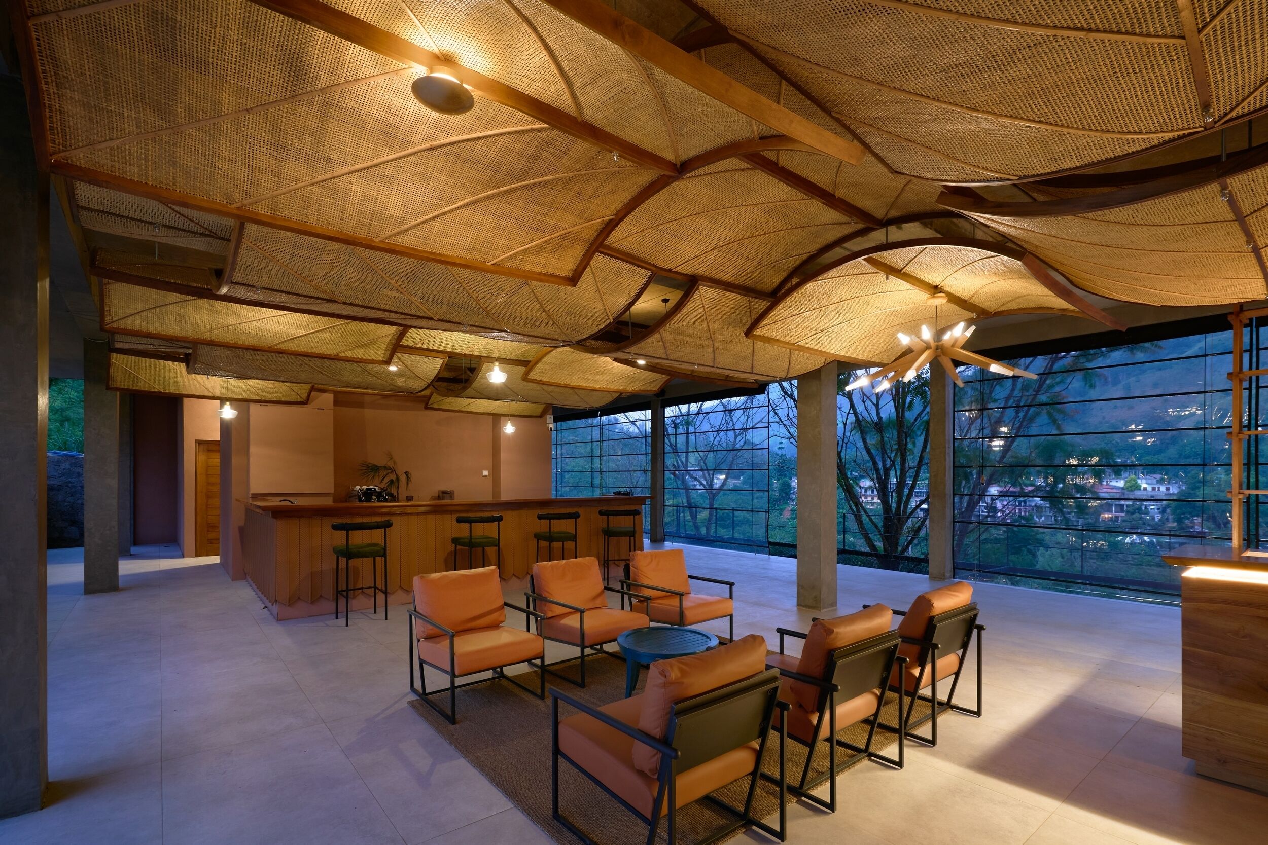 A spacious lounge area with a high ceiling, large windows, and a central seating arrangement.