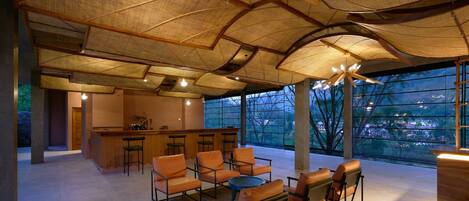 A spacious lounge area with a high ceiling, large windows, and a central seating arrangement.