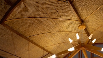 A room with a woven ceiling and a wooden ceiling fan.