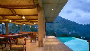 Un espace extérieur aménagé pour les repas, avec des tables et des chaises, une piscine et une vue sur un paysage montagneux.
