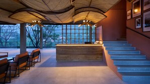 Un vestíbulo moderno con mostrador de recepción de madera, zona de estar y escalera.