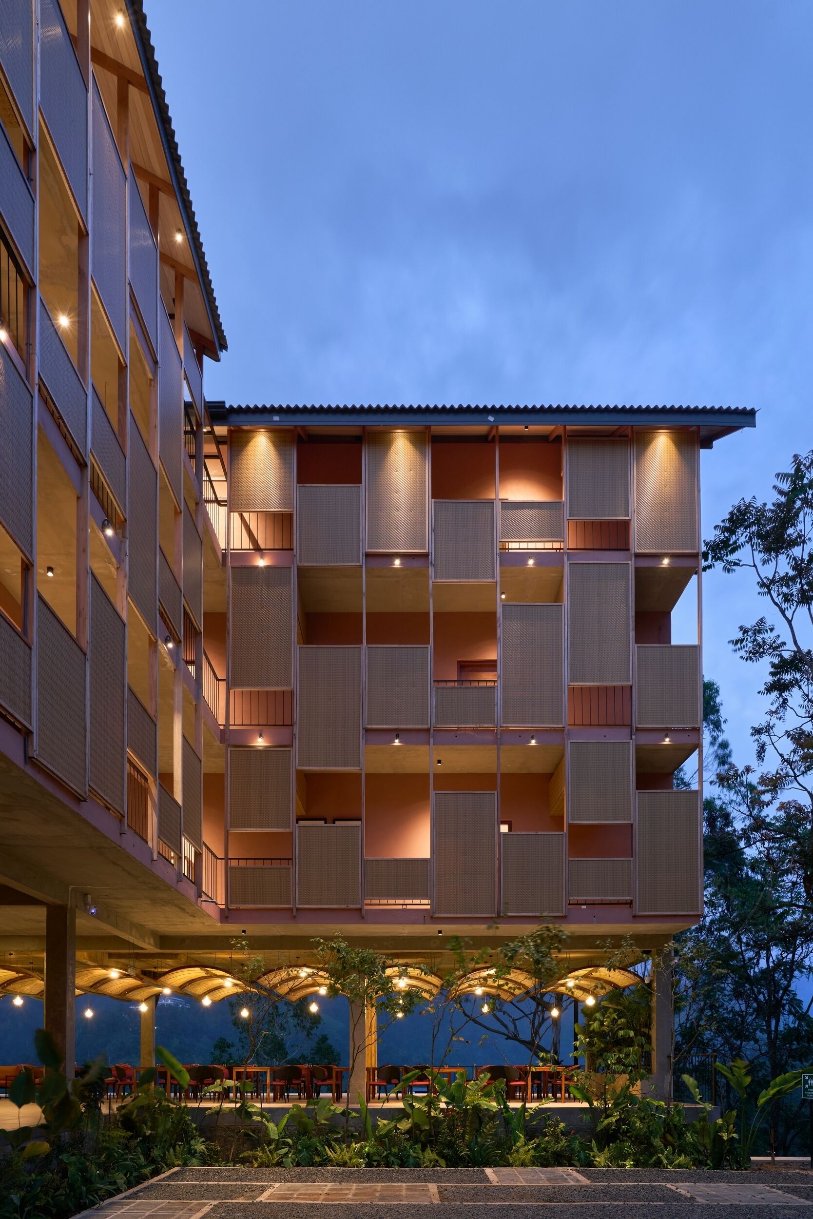 A multi-story building with a covered outdoor seating area and a pool.