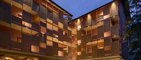 A multi-story hotel with a covered outdoor seating area and a staircase leading to the entrance.