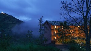 Un edificio moderno con techo inclinado, rodeado de árboles y niebla.