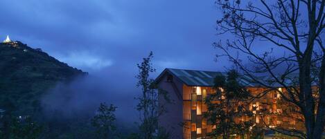 A modern building with a sloped roof, surrounded by trees and fog.