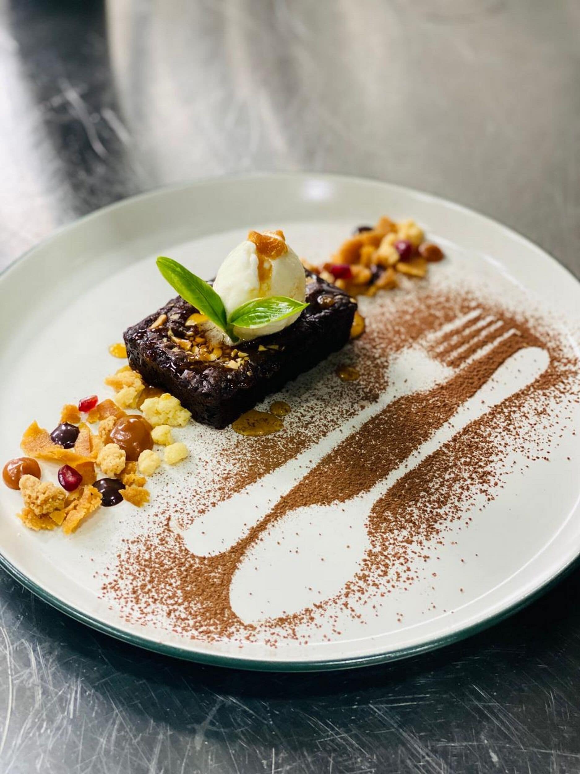 En desserttallrik med en chokladkaka, glass och garnering, serverat på en vit tallrik.