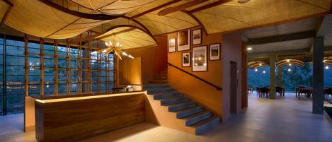 A modern reception area with a wooden reception desk, a staircase, and framed pictures on the wall.