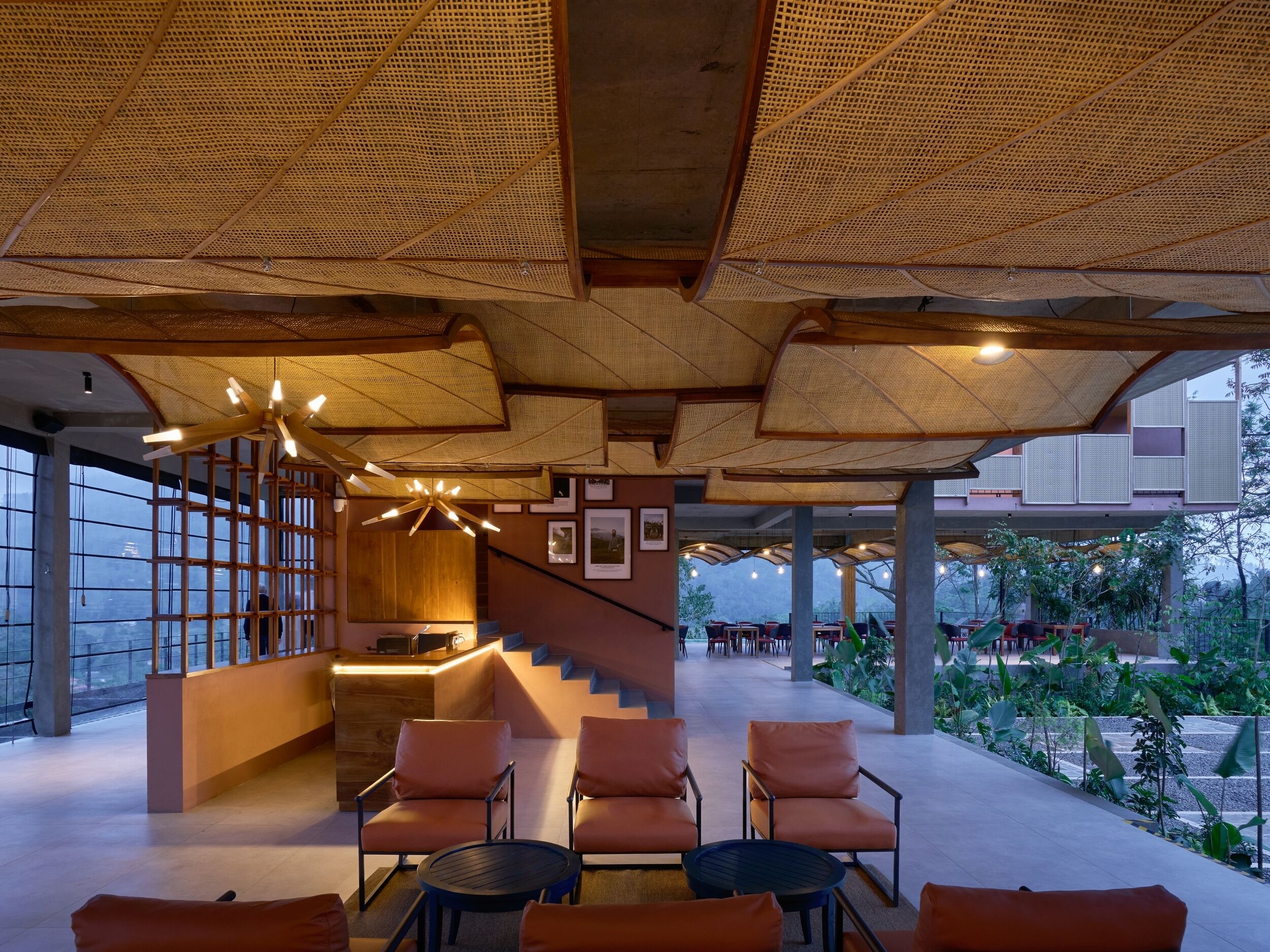 A modern interior with a reception desk, seating area, and staircase leading to an outdoor terrace.