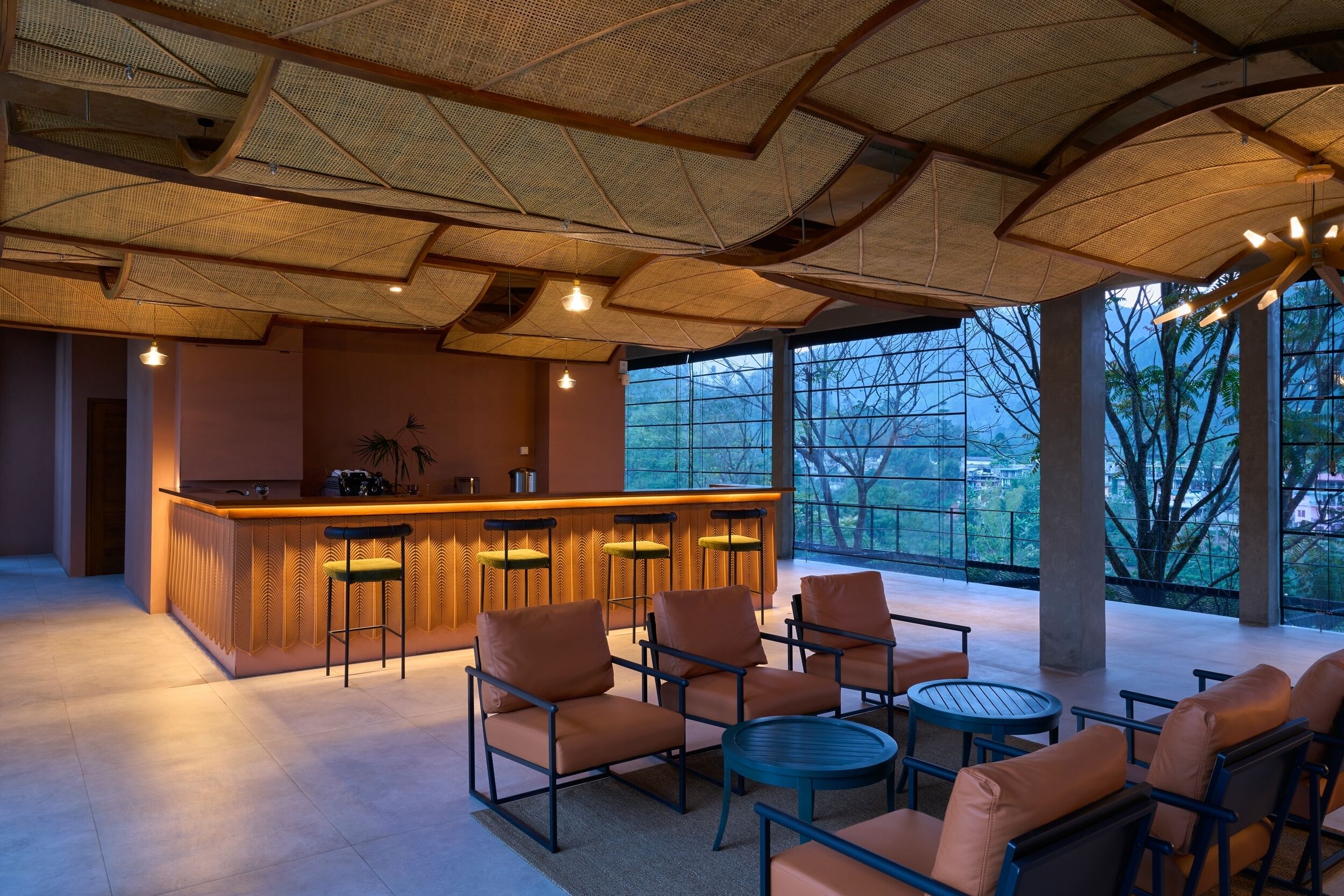 Eine moderne Bar mit Bar, Sitzgelegenheiten und großen Fenstern mit Blick auf Bäume und Gebäude.