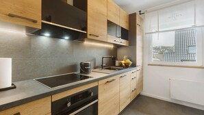 Une cuisine moderne avec des meubles en bois, un évier en acier inoxydable et un four encastré.