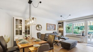 Un espace repas comprenant une table en bois, des chaises et une vue sur l’extérieur grâce à de grandes fenêtres.