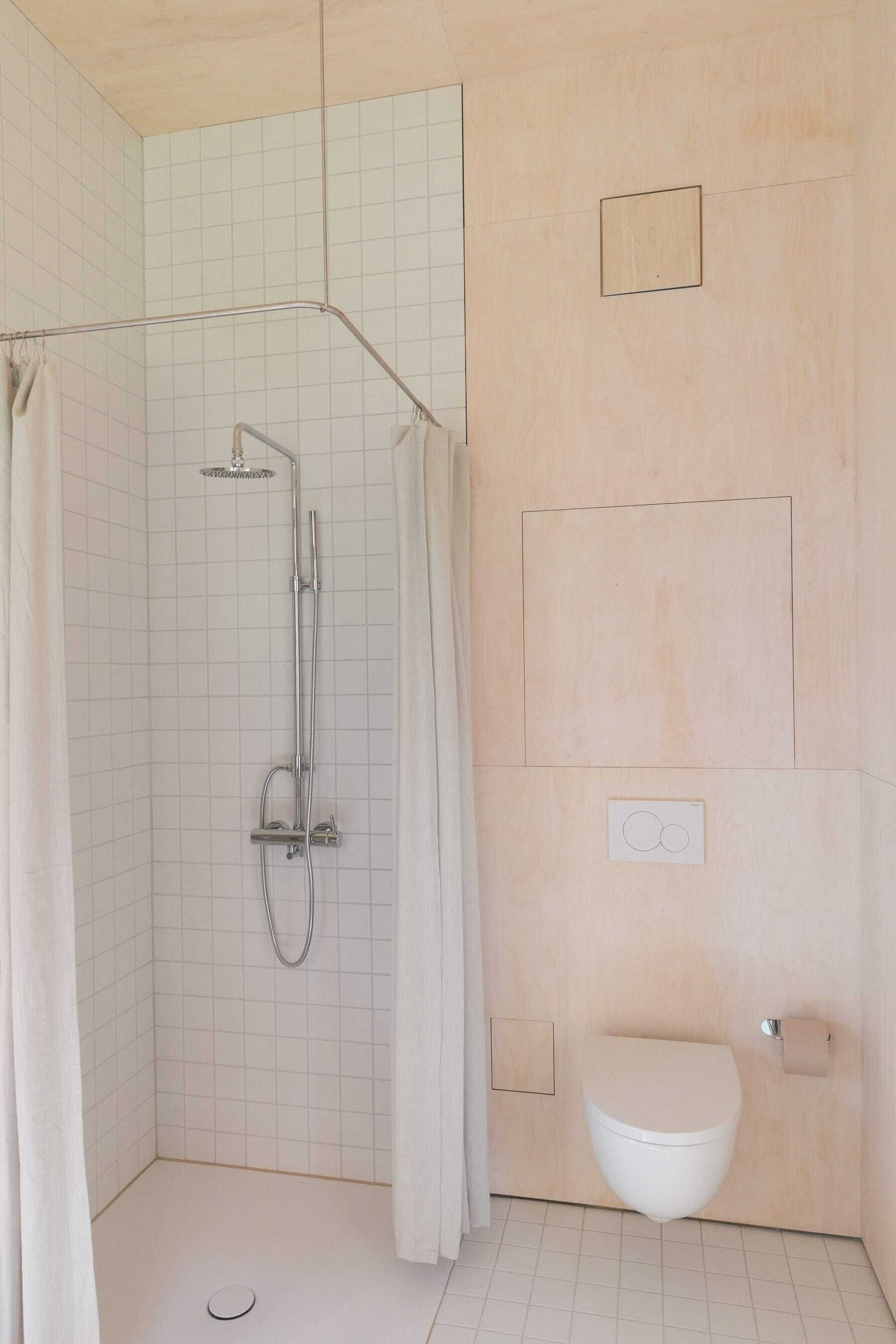 A bathroom with a shower, toilet, and a towel rack.