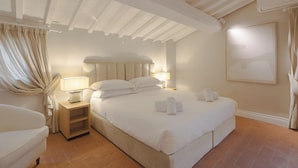 Une chambre d’hôtel avec un grand lit, des lampes de chevet, une table de chevet en bois et une tête de lit.
