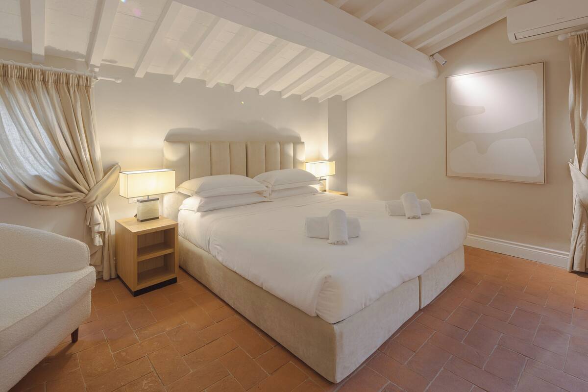 A hotel room with a large bed, bedside lamps, a wooden nightstand, and a headboard.