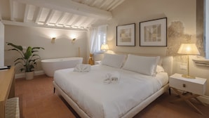 Une chambre avec un grand lit, une baignoire et une plante en pot.