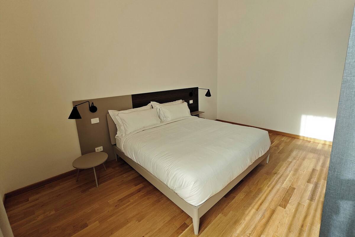 Una camera da letto con un letto, un comodino, una lampada e un tavolino rotondo.