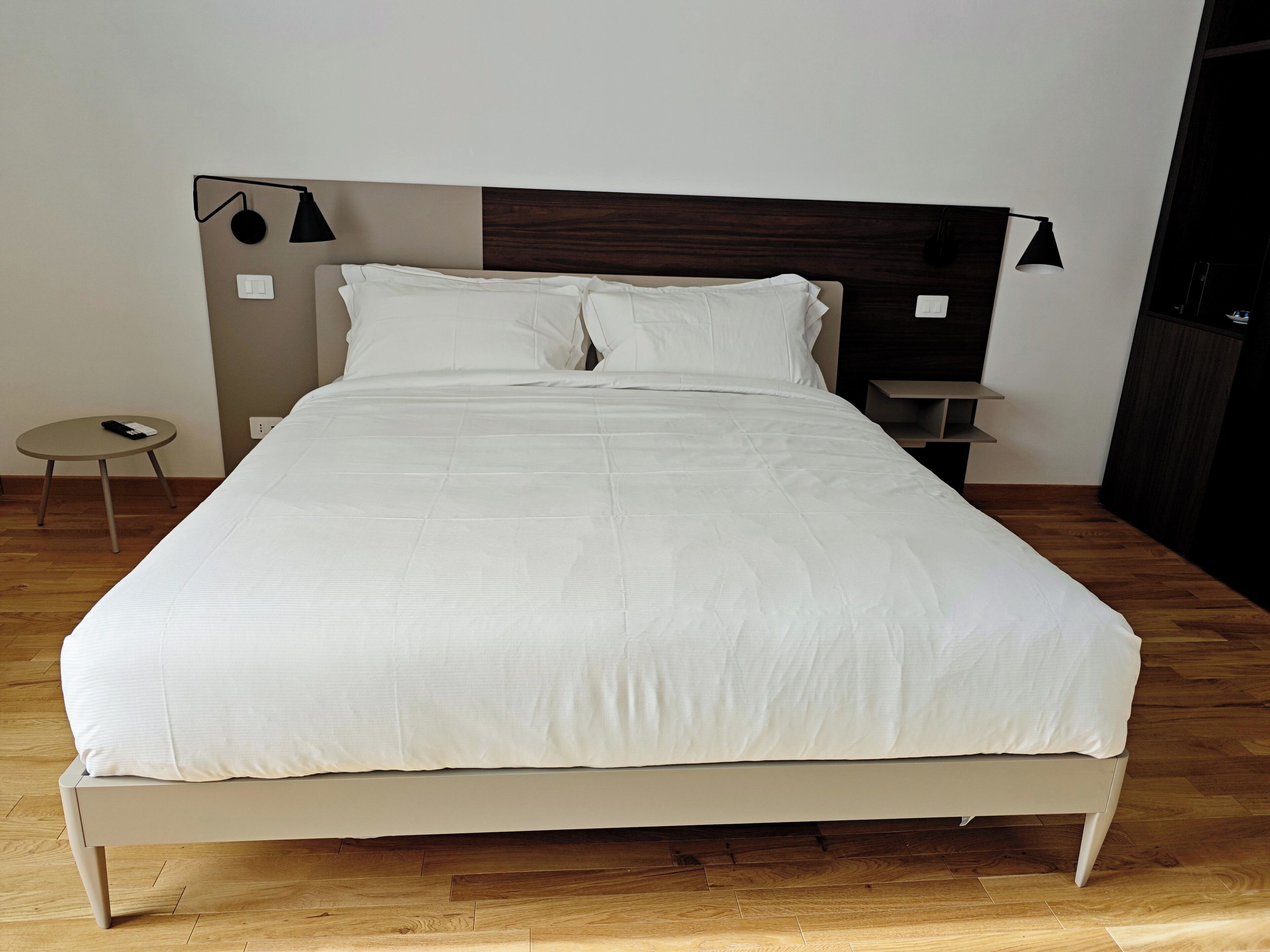 A large bed with white bedding, a wooden headboard, and two bedside tables with lamps.