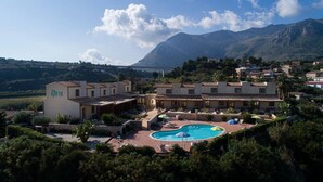 Ett semesterparadis med en swimmingpool, omgivet av frodig grönska och med ett bergigt landskap i bakgrunden.