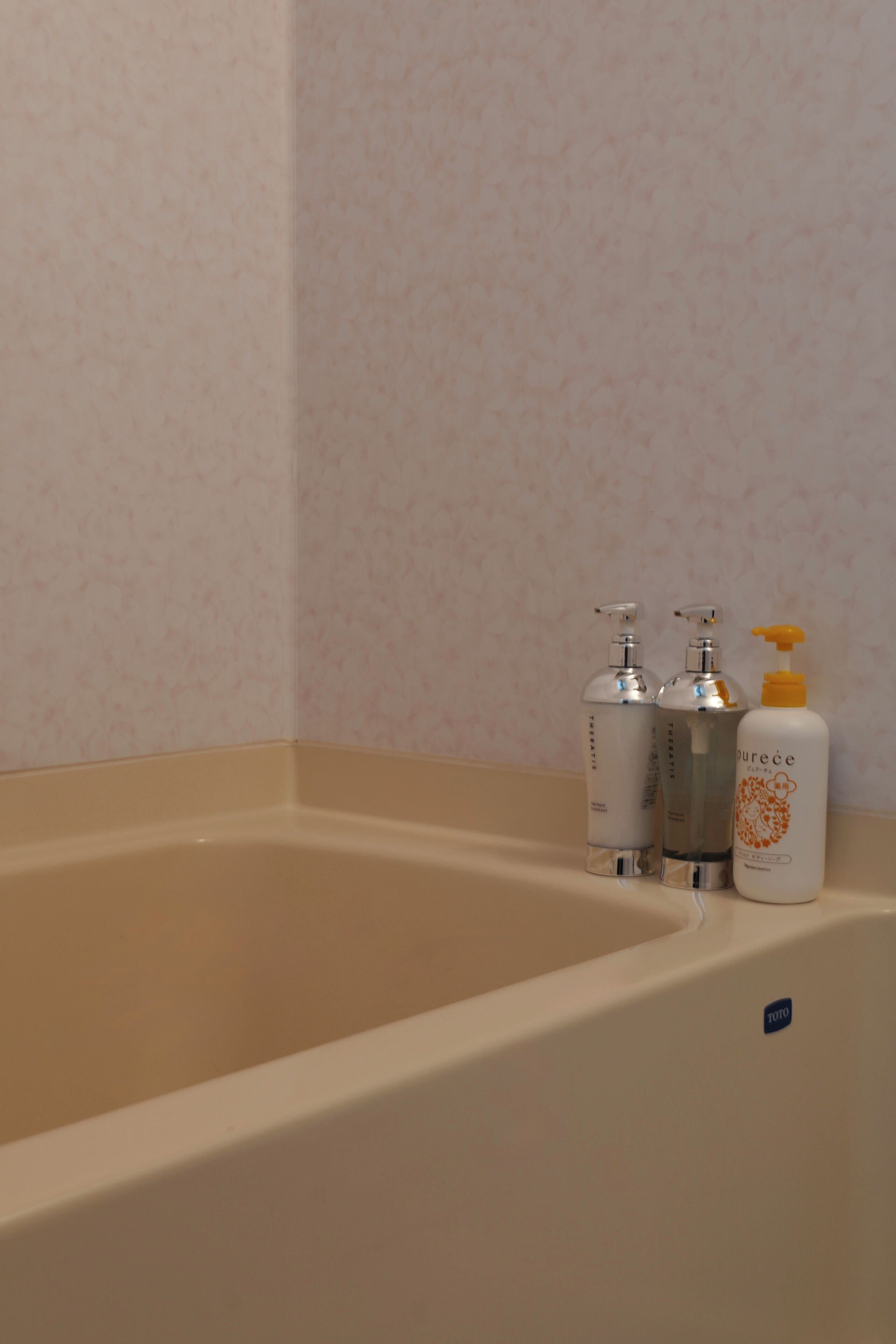 A bathtub with three bottles of toiletries.