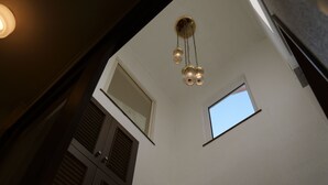 A high ceiling with a pendant light fixture, a small skylight, and a large window.
