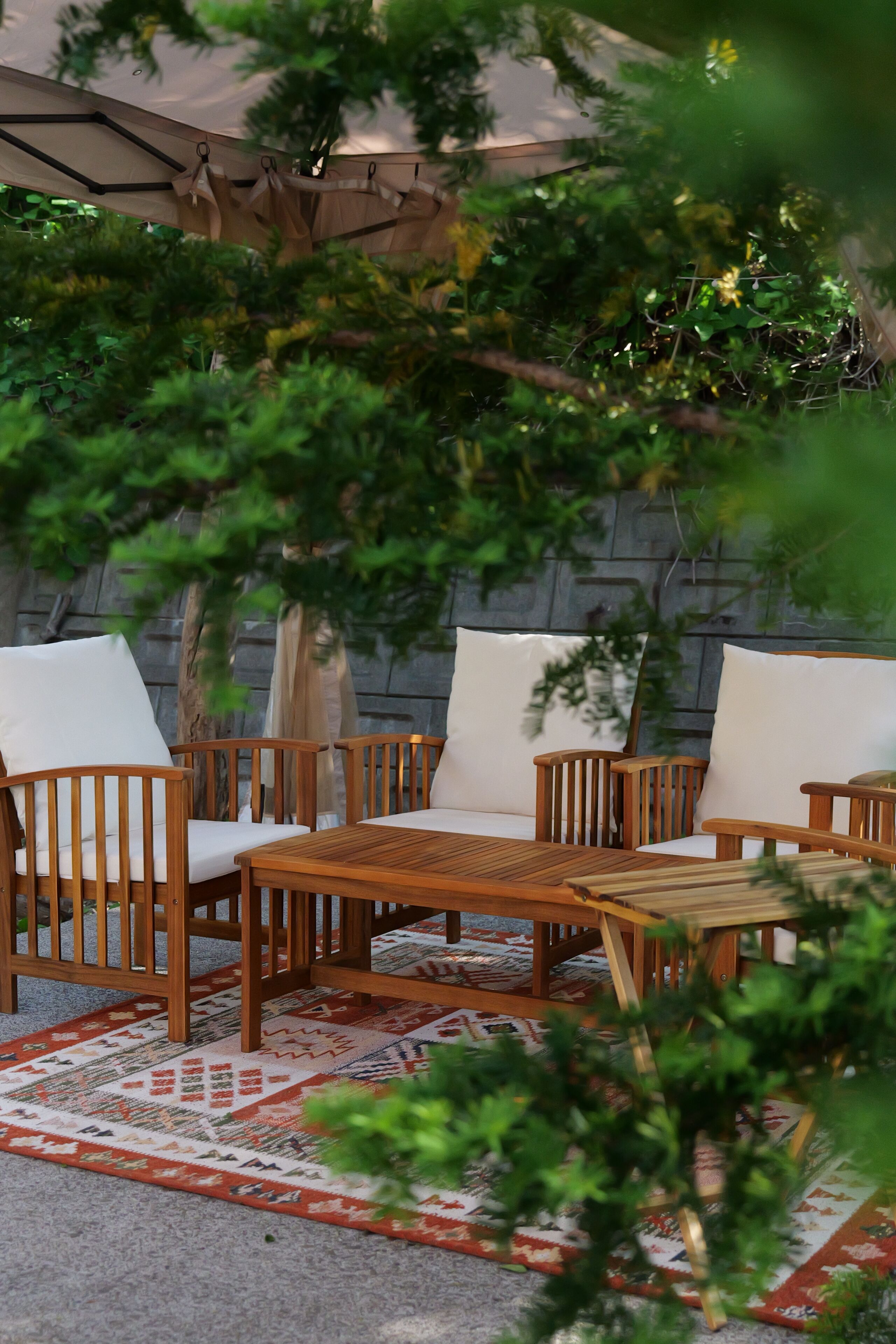 A patio area with wooden furniture, including chairs and a table, under a canopy.